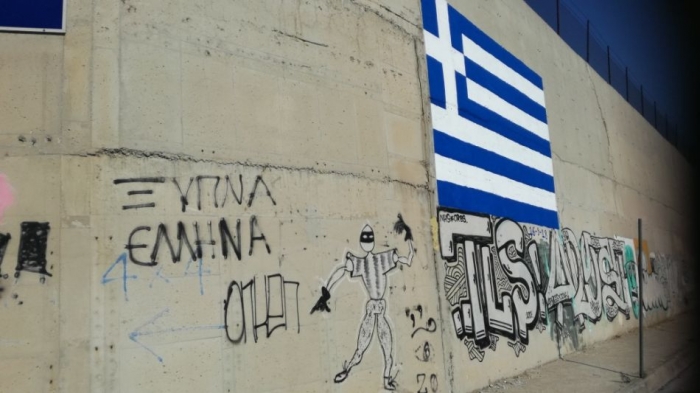Στον εισαγγελέα με φόντο την ελληνική σημαία